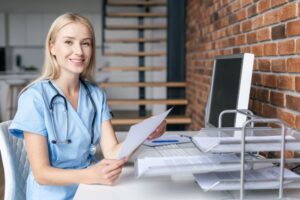 A doctor sits at a desk, looking over papers